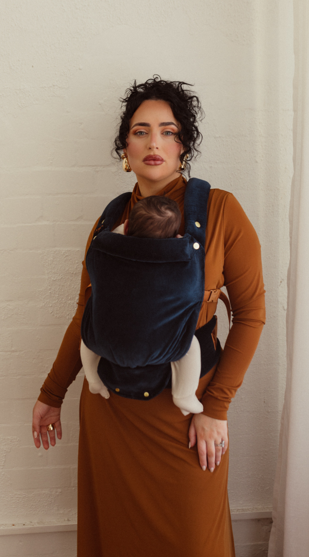 Mama Brittany wears the Luna Velvet Clip Carrier 2.0 in a beautiful studio setting. The rich blue tones compliment any wardrobe and streamlined padding make for a comfortable and sleek fit.